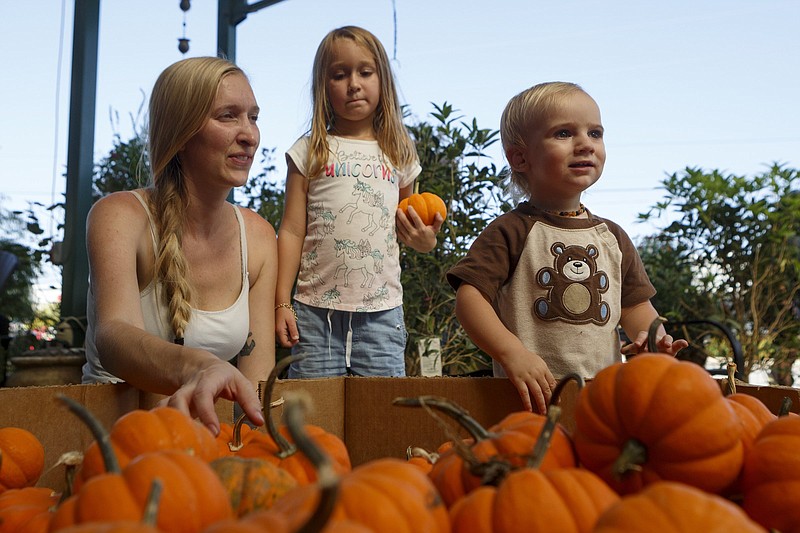 Staff photo by C.B. Schmelter / Lauren Candelaria and her children, 4-year-old Lydia and 1-year-old Jaxon, check out the pumpkins during the festival.