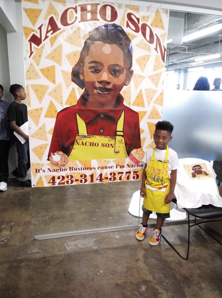 Contributed photo by Shea Jennings / Zi'on Jones stands in front of a sign featuring the logo of his business, Nacho Son.