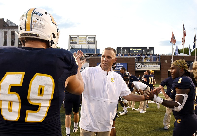 Staff photo by Robin Rudd / UTC coach Rusty Wright congratulates football players Cole Strange, left, and Drayton Arnold after the Mocs opened their SoCon schedule with a 60-36 homecoming win against Western Carolina on Sept. 28.