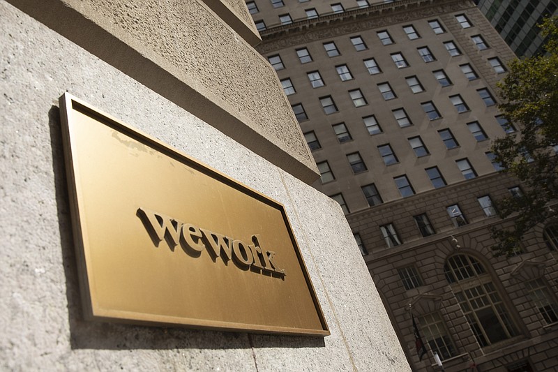 A WeWork sign hangs on a building, Monday, Sept. 30, 2019, in New York. WeWork says it is withdrawing its initial public offering less than a week after its controversial CEO stepped aside from the troubled company. (AP Photo/Mark Lennihan)