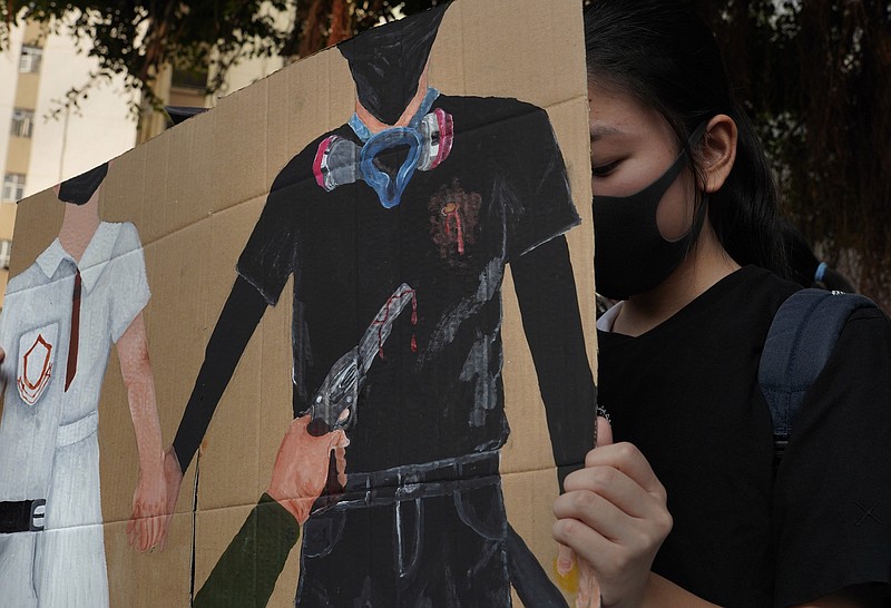 A supporter raises a printing featuring a protester shot in the chest by police during a strike in Hong Kong, Wednesday, Oct. 2, 2019. Hundreds of students at a Hong Kong college have staged a strike to condemn police shooting of a teenager during widespread violence in the semi-autonomous Chinese territory at pre-democracy protests that marred China's National Day. (AP Photo/Vincent Yu)