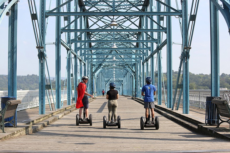 Staff photo by Erin O. Smith / From left, Kevin Shurmer of Chattanooga Segway Tours lead Sabrina Bodon, a staff writer with Chatter Magazine, and her brother, Matthew Bodon, on a tour across Walnut Street Bridge Monday, August 19, 2019 in Chattanooga, Tennessee.
