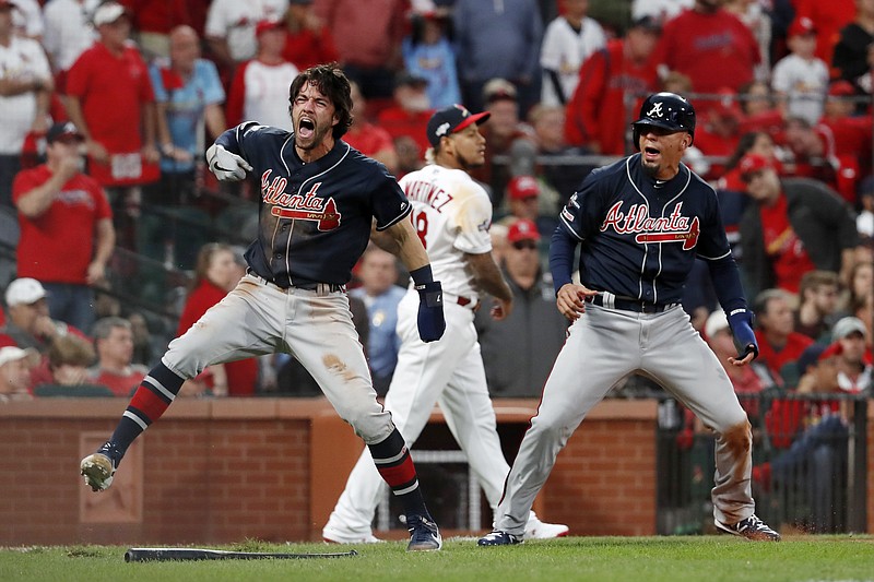 AP photo by Jeff Roberson / The Atlanta Braves' Dansby Swanson, left, and Rafael Ortega celebrate after scoring as St. Louis Cardinals relief pitcher Carlos Martinez walks in the background during the ninth inning Sunday in St. Louis. The Braves rallied to win 3-1 and move within a victory of taking the best-of-five NL Division Series. Game 4 is today in St. Louis.