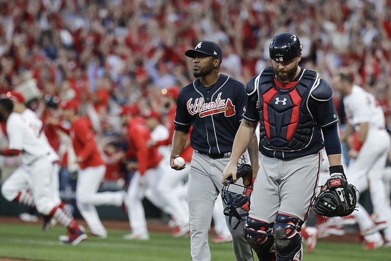 Atlanta Braves' Julio Teheran and catcher Brian McCann walk to the dugout after St. Louis Cardinals' Yadier Molina hit a sacrifice fly to score Kolten Wong for the winning run during the 10th inning in Game 4 of a baseball National League Division Series, Monday, Oct. 7, 2019, in St. Louis. (AP Photo, Charlie Riedel)