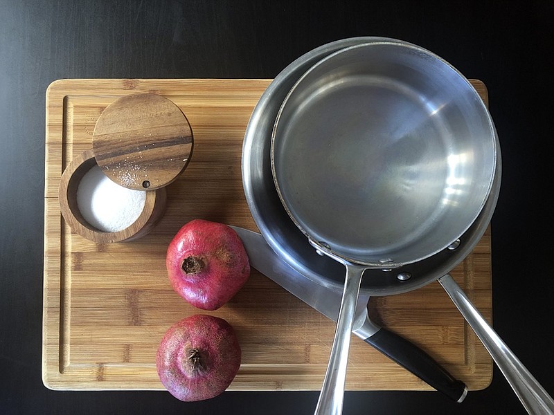 This Oct. 2, 2019 photo shows kosher salt, a couple of pans, a chefs knife and two pomegranates on a cutting board displayed in New York. (Katie Workman via AP)


