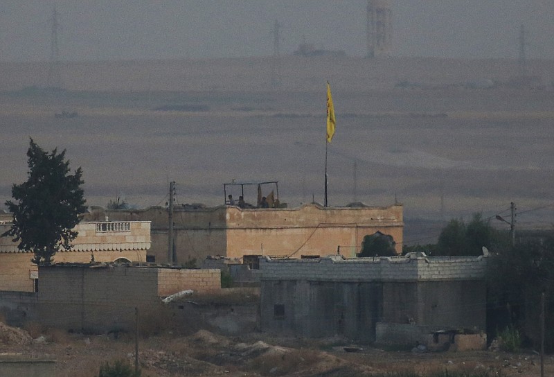 In this photo taken from the Turkish side of the border between Turkey and Syria, in Akcakale, Sanliurfa province, southeastern Turkey, members of the Kurdish People's Protection Units, or YPG, hold a position on a building in the Syrian town of Tel Abyad, Tuesday, Oct. 8, 2019. The Turkey - Syria border has became a hot spot as Turkish Vice President Fuat Oktay said Turkey was intent on combatting the threat of Syrian Kurdish fighters across its border in Syria. (AP Photo/Lefteris Pitarakis)