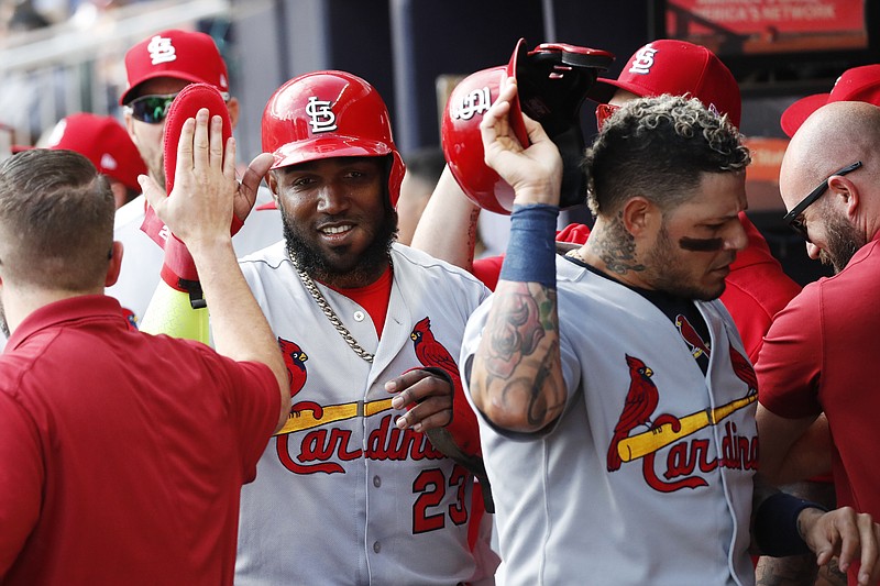 AP photo by John Bazemore / The St. Louis Cardinals' Marcell Ozuna, left, and Yadier Molina, are greeted by teammates after scoring off Tommy Edman's double during the first inning of Game 5 of their NL Division Series against the Atlanta Braves on Wednesday in Atlanta.