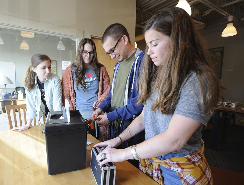 Staff photo by Tim Barber/ Emily Valdes, left, observes as Paige Moffett, Jeff Grizzard and Molly Grizzard, gather clues to unlock several padlocks on lock boxes and find 12 total clues to escape the Language South Spanish  Immersion program set up as an escape room for adults to learn the language.