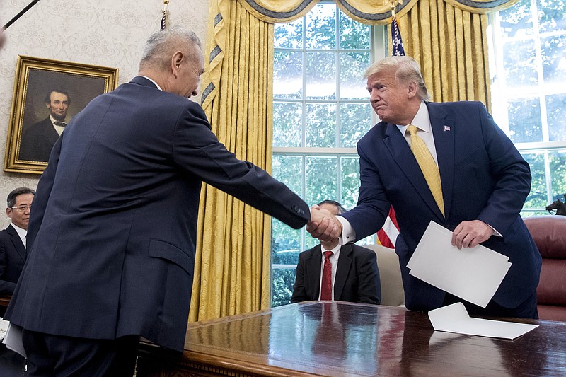 In this Oct. 11, 2019, file photo, U.S. President Donald Trump, right, shakes hands with Chinese Vice Premier Liu He after being given a letter in the Oval Office of the White House in Washington. China's trade with the United States fell by double digits again in September amid a tariff war that threatens to tip the global economy into recession. (AP Photo/Andrew Harnik, File)