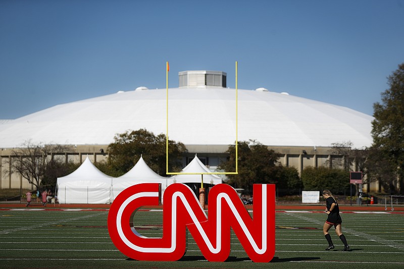 A student athlete passes a CNN sign on an athletic field outside the Clements Recreation Center on Monday, Oct. 14, 2019, where the CNN/New York Times will host the Democratic presidential primary debate Tuesday at Otterbein University in Westerville, Ohio. (AP Photo/John Minchillo)
