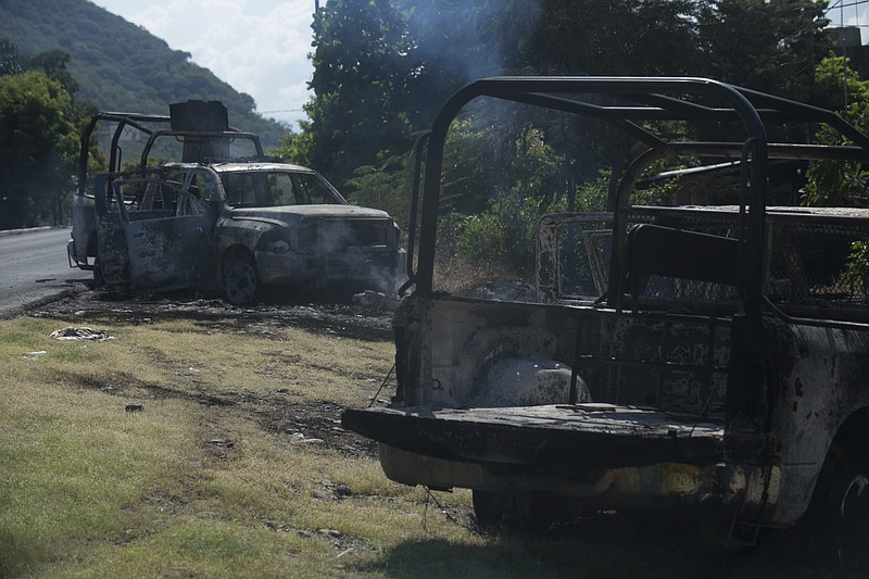 Charred trucks that belong to the Michoacan state police stand on the roadside after they were attacked in El Aguaje, Mexico, Monday, Oct. 14, 2019. At least 13 police officers were killed and nine others injured in the ambush. (AP Photo/Armando Solis)