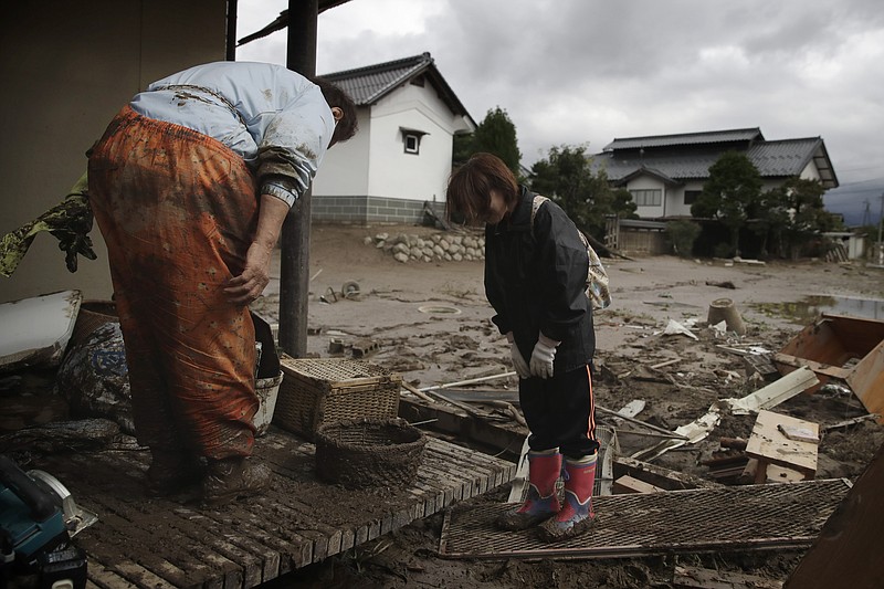 Michiko Yoshimura, left, bows to her neighbor as they comfort each other while cleaning up her home damaged by Typhoon Hagibis Tuesday, Oct. 15, 2019, in Nagano, Japan. More victims and more damage have been found in typhoon-hit areas of central and northern Japan, where rescue crews are searching for people still missing. (AP Photo/Jae C. Hong)