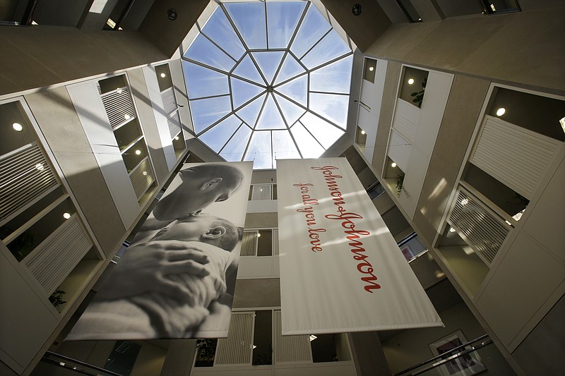 FILE - In this July 30, 2013, file photo, large banners hang in an atrium at the headquarters of Johnson & Johnson in New Brunswick, N.J.  Johnson & Johnson has agreed to a $117 million multistate settlement over allegations it deceptively marketed its pelvic mesh products, which support women's sagging pelvic organs. (AP Photo/Mel Evans, File)
