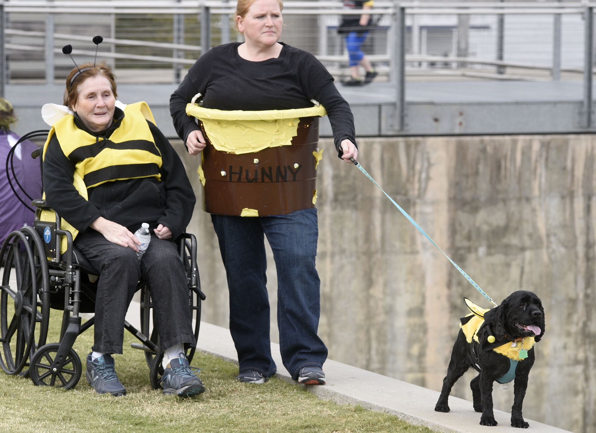Staff Photo by Robin Rudd/ From left, Hazel Grimes is a bee, Christy Grimes is the jar of honey and Rocky plays a bee at the event. Hundreds of animals lovers gathered to raise money for the Humane Educational Society at the 17th annual Paws in the Park. The event included a walk, dog and human costume contest, and a dog cake-eating contest. Ross's Landing Park was the site of the event on October 19, 2019.