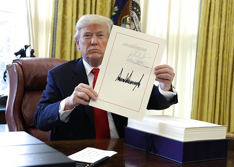 FILE - In this Dec. 22, 2017, file photo, President Donald Trump displays the $1.5 trillion tax overhaul package he signed in the Oval Office of the White House in Washington. Trump is now three for three. Each year of his presidency, he has issued more executive orders than did former President Barack Obama during the same time-span. ()