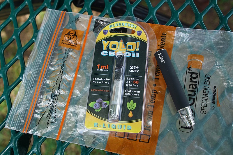 In this May 8, 2019, file photo, a Yolo! brand CBD oil vape cartridge sits alongside a vape pen on a biohazard bag on a table at a park in Ninety Six, S.C. More than 50 people around Salt Lake City had been poisoned by the time the outbreak ended early last year, most by a vape called Yolo!, the acronym for "you only live once." (AP Photo/Allen G. Breed, File)