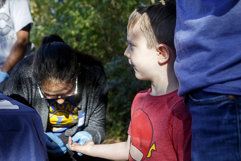 Staff photo by C.B. Schmelter / Kavina Patel, left, takes a blood sample for lead testing from 4-year-old Fletcher Grosso, as Patrick Wallace stands by, at the University of Tennessee at Chattanooga Lions Club and UTC Masters of Public Health table during a public ribbon cutting ceremony for a Lead Education Station at the Southside Branch of the Chattanooga Public Library on Wednesday, Oct. 23, 2019 in Chattanooga, Tenn.