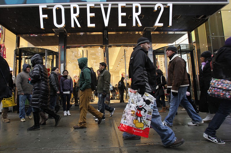 FILE - In this Dec. 26, 2010 file photo, people walk past a Forever 21 store in New York's Times Square. The population of the U.S. has grown by 8 million people since the previous record was set. That means there were millions more shoppers in stores this Christmas, driving up the sales total. But the average amount of spending per person was down from a few years ago, suggesting consumers are still slower to pull out their wallets. (AP Photo/Mary Altaffer, file)