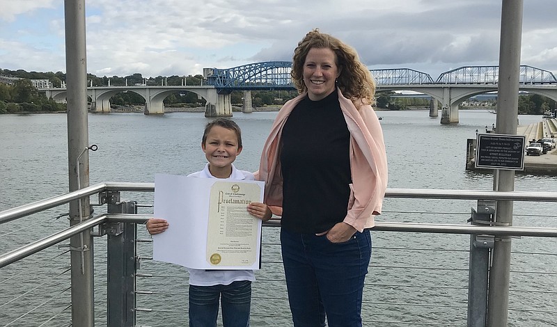 Cash Daniels, known as 'The Conservation Kid,' holds a proclamation from Chattanooga Mayor Andy Berke as he poses in front of the Tennessee River with Kathleen Gibi, Executive Director at Keep the Tennessee River Beautiful, in October 2019. / Contributed photo by Keep the Tennessee River Beautiful