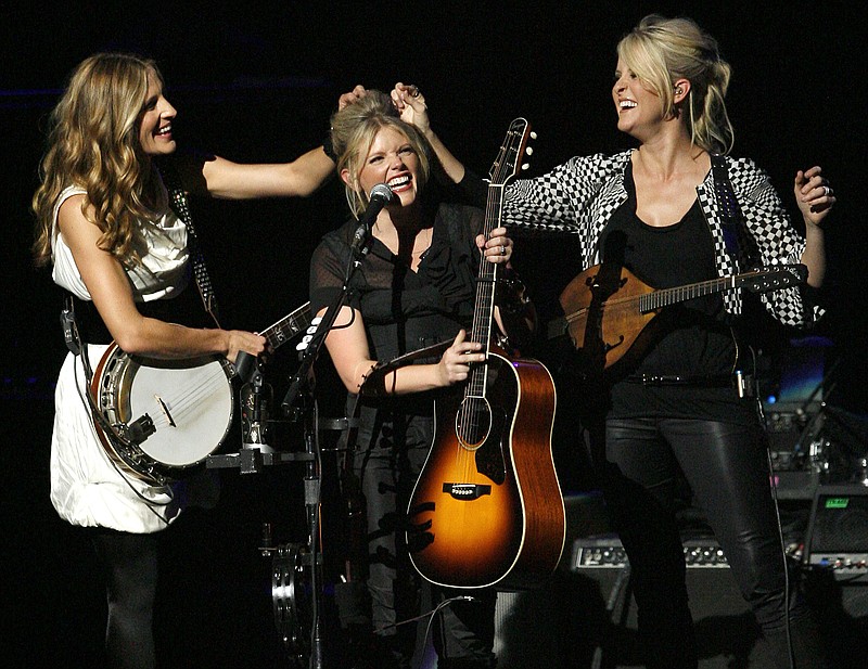 Associated Press file photo — In this Oct. 18, 2007 file photo, Emily Robison, left, and Martie Maguire, right, adjust Natalie Maines' hair as the Dixie Chicks perform at the new Nokia Theatre in Los Angeles. The award-winning group took to Instagram in June 2019 to tease a new album. It is their first in 13 years.
