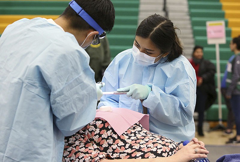Eint Ei, a student volunteer from the University of Tennessee at Kentucky, helps Dr. Fred Lee extract teeth from a patent during a free clinic hosted by Remote Area Medical Sunday, March 10, 2019 at Rhea County Middle School in Evensville, Tennessee. Ei said the two had extracted 41 teeth Sunday morning.