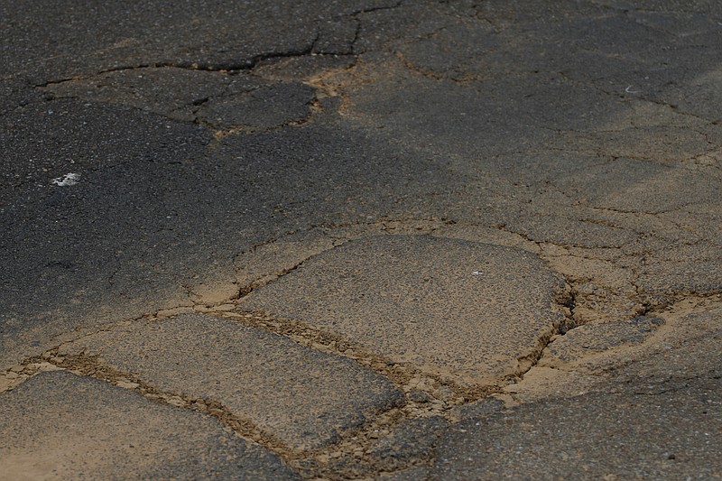 Staff File Photo / Potholes along St. Elmo Avenue are shown before the street received repairs and paving several years ago.