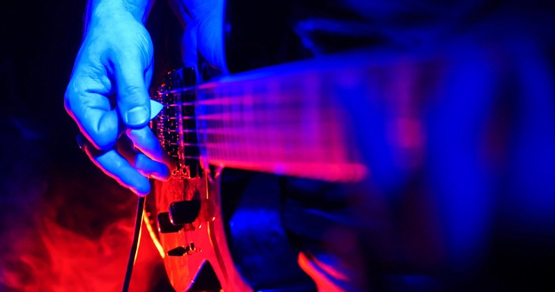 Rock concert. Guitarist plays the guitar. The guitar illuminated with bright neon lights. Focus on hands. No face shown guitar tile music tile instrument tile / Getty Images
