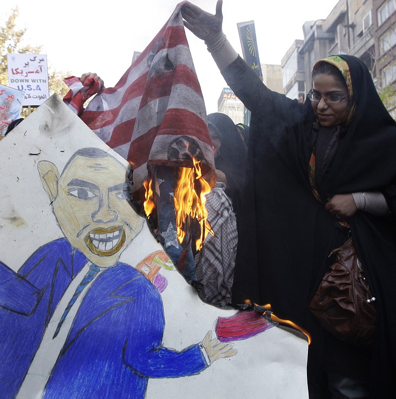 Associated Press File Photo / A female Iranian demonstrator holds up a burning representation of the U.S. flag in an annual state-backed rally in front of the former U.S. Embassy in Tehran, Iran, commemorating the anniversary of the 1979 embassy takeover by militant Islamist students.