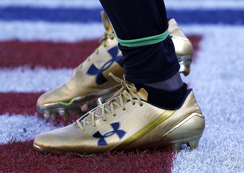 FILE- In this Dec. 10, 2017, file photo Jacksonville Jaguars running back T.J. Yeldon warms up wearing Under Armour cleats before an NFL football game against the Seattle Seahawks in Jacksonville, Fla. A strong quarter from Under Armour is being overshadowed by a federal investigation into the company’s accounting practices. The athletic gear maker reported better than expected profit and revenue for the third quarter Monday, Nov. 4, 2019, but shares are down 13% before the opening bell.  (AP Photo/Stephen B. Morton, File)