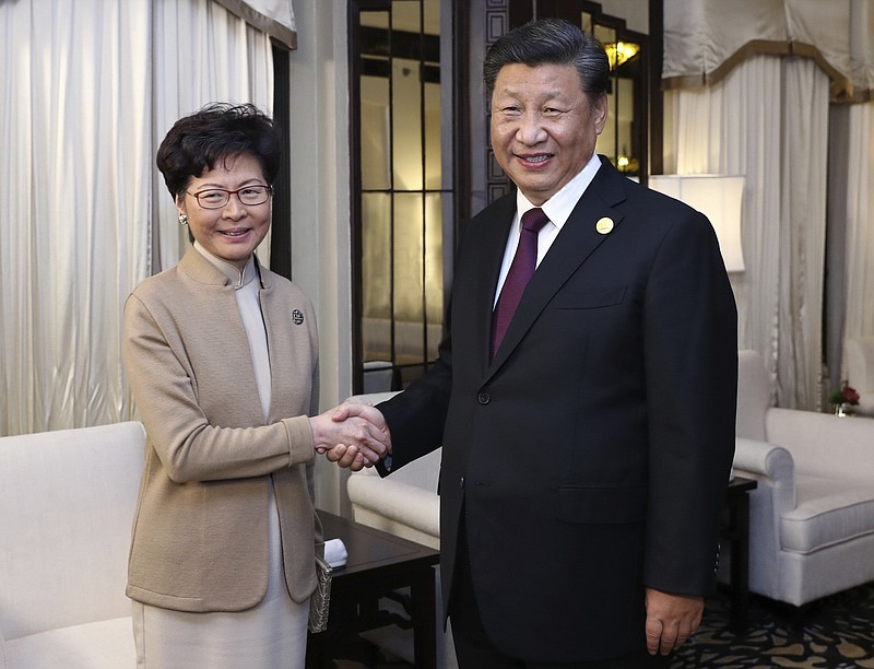 In this Monday, Nov. 4, 2019, photo released by China's Xinhua News Agency, Chinese President Xi Jinping poses with Hong Kong Chief Executive Carrie Lam for a photo during a meeting in Shanghai, China. Lam is here for the second China International Import Expo (CIIE). (Ju Peng/Xinhua via AP)