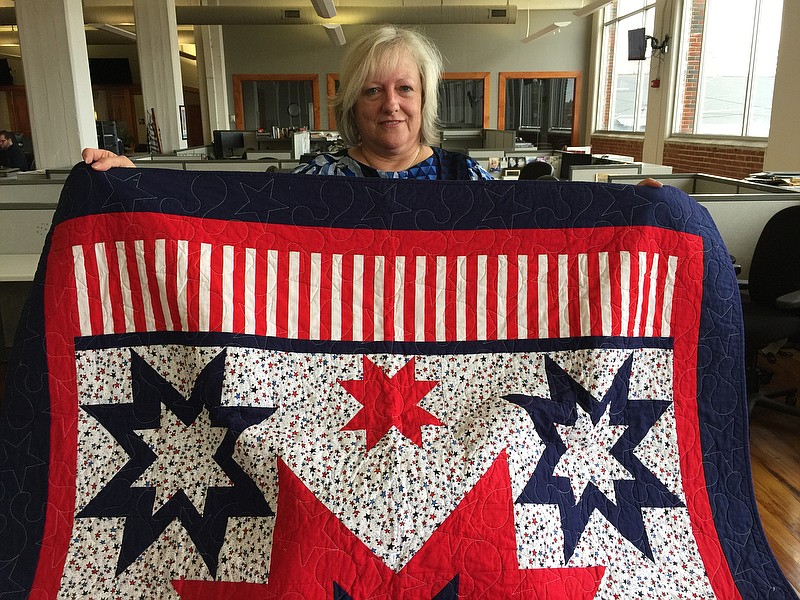 Photo by Mark Kennedy/  Karen Downer shows off one of the quilts her group, the Quilts of Valor Foundation, has made for veterans.