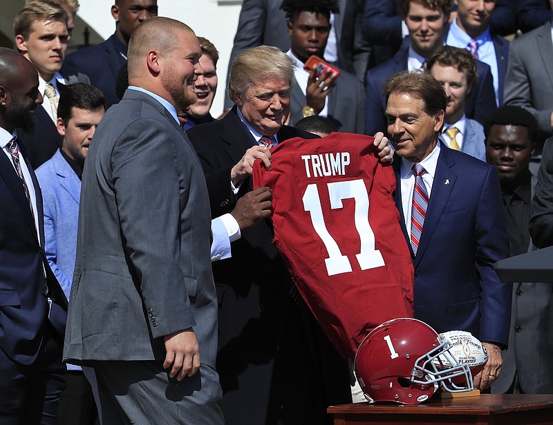 AP photo by Manuel Balce Ceneta / President Donald Trump holds up a University of Alabama football jersey presented to him by Crimson Tide coach Nick Saban, right, during a ceremony honoring the 2017 national champions on the South Lawn of the White House in April 2018. The president plans to attend Alabama's game Saturday against visiting LSU.