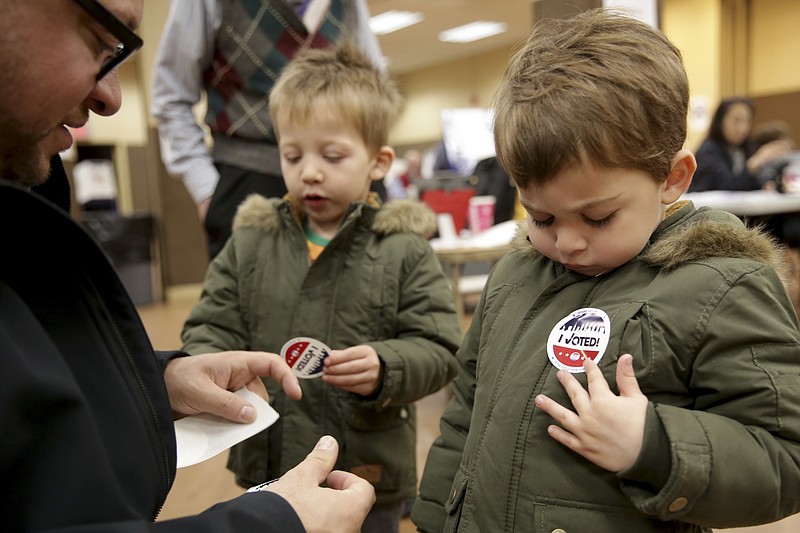 Twins Amir, right, and Milo Klatzkin, 3, put on their "I Voted" stickers after their father Barry Klatzkin, left, voted at a polling site in New York, Tuesday, Nov. 5, 2019. New York's first election with early voting is reaching its conclusion as people across the state cast ballots in county and municipal races. With no federal or statewide contests on the ballot Tuesday, turnout is expected to be low, but this year's contests are serving as a rehearsal for next year's blockbuster presidential race. (AP Photo/Seth Wenig)