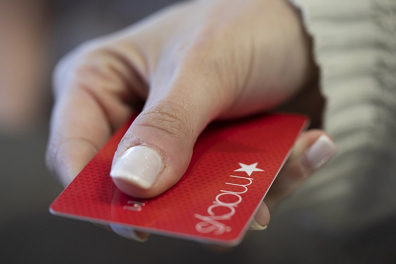 FILE - In this Aug. 11, 2019, file photo a woman holds a Macy's card in New Orleans. Signups for retailer credit cards soar during the holidays. (AP Photo/Jenny Kane, File)