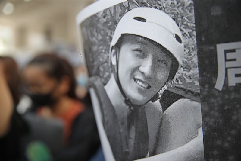 A protester holds up a photo of Chow Tsz-Lok as they disrupt a graduation ceremony at the University of Science and Technology in Hong Kong on Friday, Nov. 8, 2019. The ceremony was cut short, and black-clad masked students turned the stage into a memorial for Chow who fell off a parking garage after police fired tear gas during clashes with anti-government protesters and died Friday. (AP Photo/Kin Cheung)