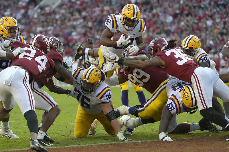 AP photo by Vasha Hunt / LSU running back Clyde Edwards-Helaire dives over Alabama's Raekwon Davis (99) and Markail Benton (36) to score a touchdown in the first half on Nov. 9, 2019, in Tuscaloosa. The SEC West rivals are set to play Nov. 7 this year.