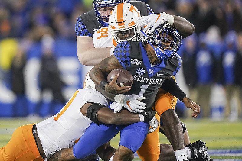 AP photo by Bryan Woolston / Kentucky quarterback Lynn Bowden Jr.  is tackled by Tennessee linebacker Quavaris Crouch, left, and defensive lineman Matthew Butler during the first half of Saturday night's SEC East matchup in Lexington, Ky.