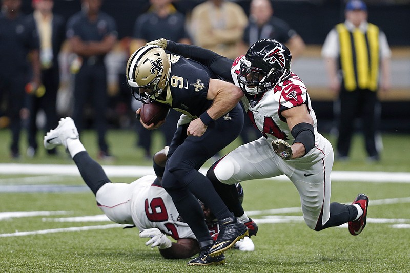 AP photo by Butch Dill / New Orleans Saints quarterback Drew Brees is sacked by Atlanta Falcons defensive end Vic Beasley Jr., right, and defensive tackle Grady Jarrett in the second half of Sunday's game in New Orleans.