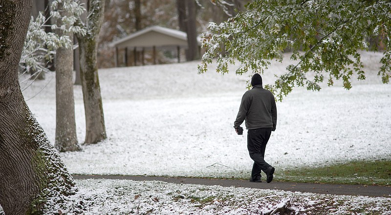 A walker takes a stroll through the light snow at Steele Creek Park in Bristol Tennessee on Tuesday, Nov. 12, 2019. Following the light snowfall, temperatures began to drop throughout the day with record cold expected overnight. (Andre Teague/Bristol Herald Courier via AP)