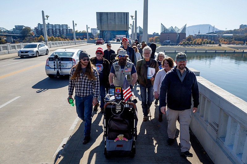 Staff photo by C.B. Schmelter / Van Booth, center, and a group of supporters walk across the Market Street Bridge towards Edley's Bar-B-Que on Wednesday, Nov. 13, 2019 in Chattanooga, Tenn. Booth, a retired U.S. Army staff sergeant, began walking from California to South Carolina in February to honor traumatized and suicidal veterans. He calls his journey Walking for Life.