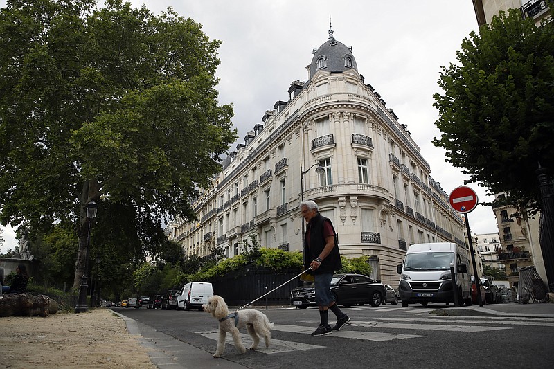 FILE - In this Aug.13, 2019 file photo, a man walks his dog next to an apartment building owned by Jeffrey Epstein in the 16th district in Paris, Tuesday, Aug. 13, 2019. Women who claim they were raped and sexually assaulted by an associate of Jeffrey Epstein are voicing disappointment at the apparent slow progress of a French police probe into their allegations and questioning the zeal of investigators who've made only limited efforts to track down other witnesses. (AP Photo/Francois Mori, File)
