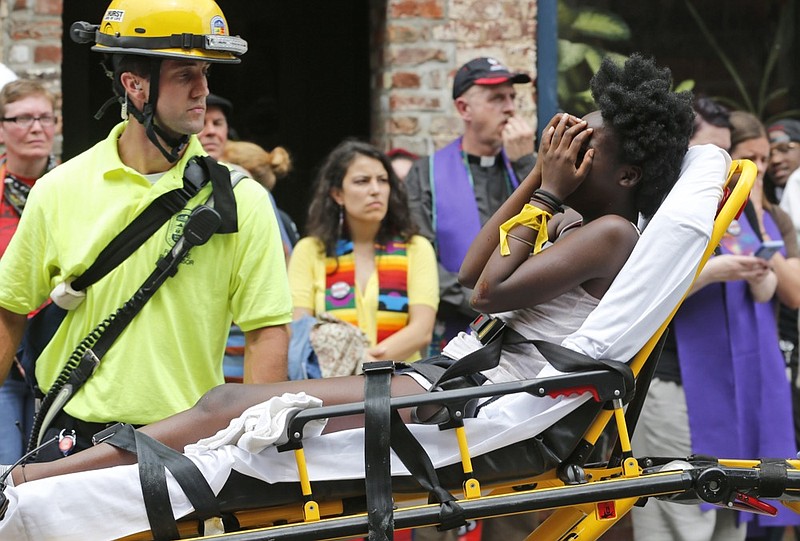 FILE - In this Aug. 12, 2017, file photo, an emergency employee helps an injured person after a neo-Nazi drove his car into a group of counter-protesters at a white nationalist rally in Charlottesville, Va. (AP Photo/Steve Helber, File)


