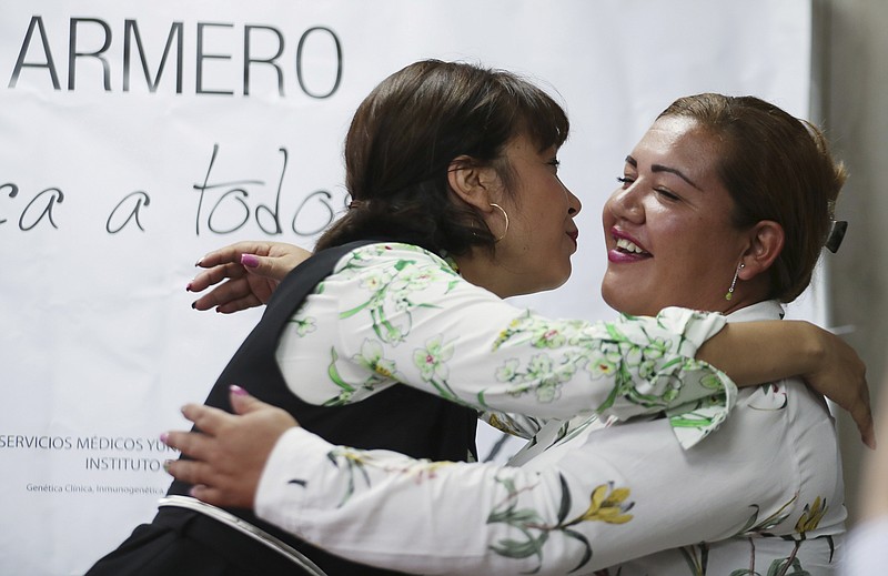 Jenifer De La Rosa, left, embraces her sister Angela Rendon after a press conference in Bogota, Colombia, Thursday, Nov. 14, 2019. The story of the sisters could be one of many involving children who were separated from their parents after the Nevado del Ruiz erupted, rescued from the rubble and later put up for adoption after no relative arrived to claim them. A genetic institute in Colombia's capital confirmed through DNA testing that Jenifer De La Rosa and Angela Rendon are sisters. (AP Photo/Fernando Vergara)