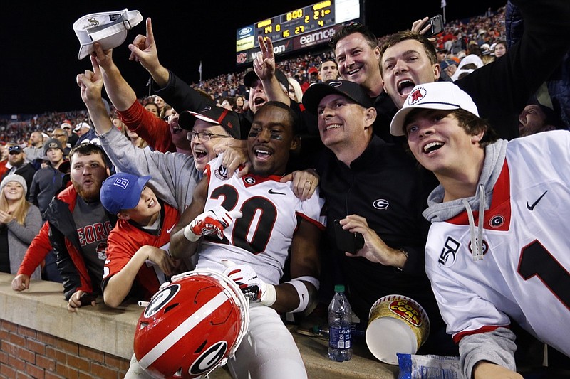 AP photo by Butch Dill / Georgia defensive back J.R. Reed celebrates with fans after the Bulldogs defeated host Auburn 21-14 on Saturday to clinch the SEC East title.