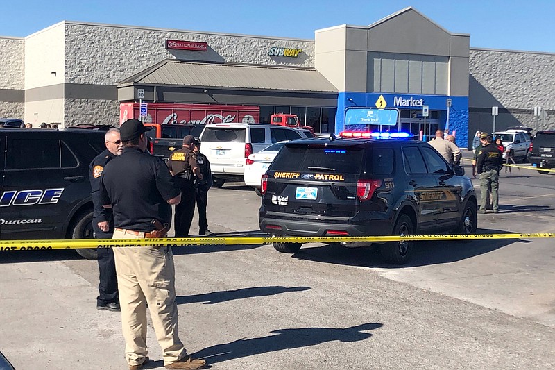 Law enforcement work the scene where two men and a woman were fatally shot Monday, Nov. 18, 2019, outside a Walmart store in Duncan, Okla. Two victims were shot inside a car and the third was in the parking lot outside the store in Duncan, Police Chief Danny Ford said. (AP Photo/Sean Murphy)