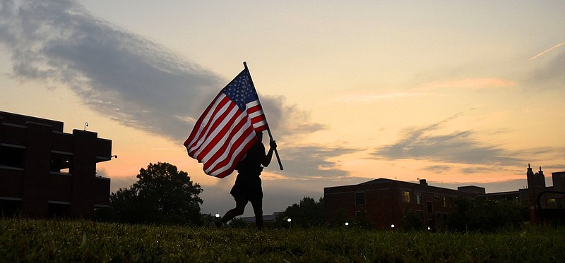 Staff File Photo By Robin Rudd / UTC ROTC graduate student Trevon Wiggins carries the American flag around Chamberlain Field at sunrise during the Military Science Department's commemoration of 9-11 in September.