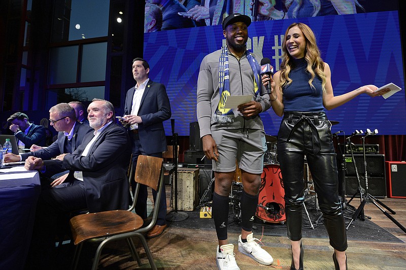 AP photo by Mark Zaleski / Tennessee Titans running back Derrick Henry laughs with MLS host Susannah Collins before announcing Nashville's second selection during a Major League Soccer expansion draft party Tuesday in Nashville. The team selected Zarek Valentin from the Portland Timbers.