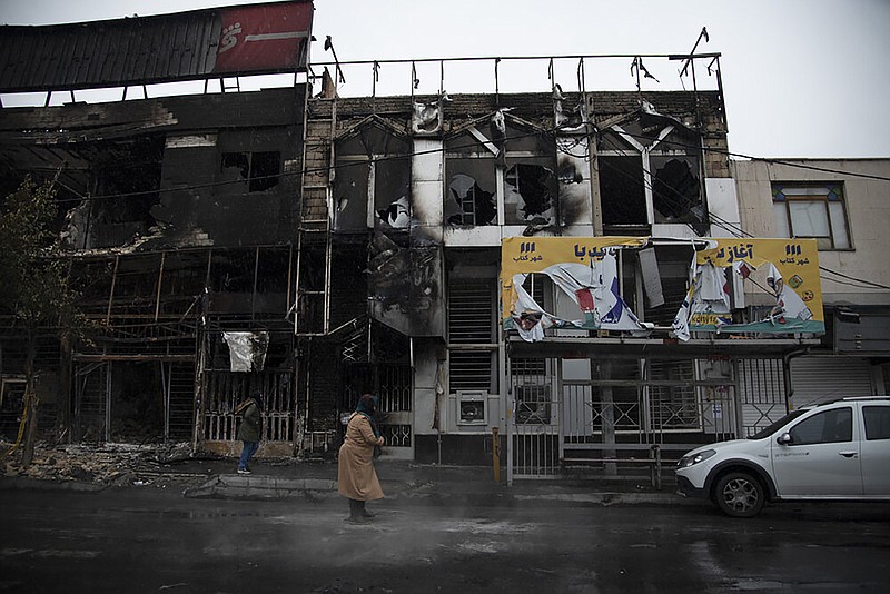 In this photo taken Monday, Nov. 18, 2019, and released by Iranian Students' News Agency, ISNA, people walk past buildings which burned during protests that followed the authorities' decision to raise gasoline prices, in the city of Karaj, west of the capital Tehran, Iran. An article published Tuesday in the Keyhan hard-line newspaper in Iran is suggesting that those who led violent protests will be executed by hanging as the unrest continues. (Masoume Aliakbar/ISNA via AP)

