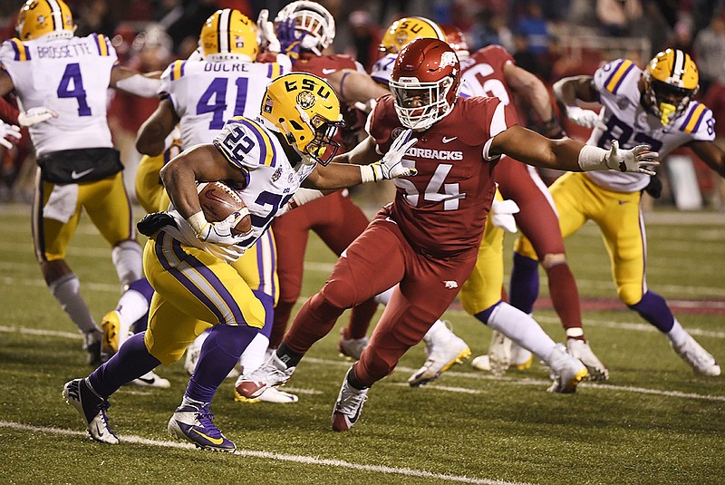 AP photo by Michael Woods / LSU running back Clyde Edwards-Helaire runs past Arkansas defender Terrell Collins during their SEC West matchup in November 2018 in Fayetteville, Ark., a 24-17 victory for LSU. The top-ranked Tigers host the struggling Razorbacks on Saturday.