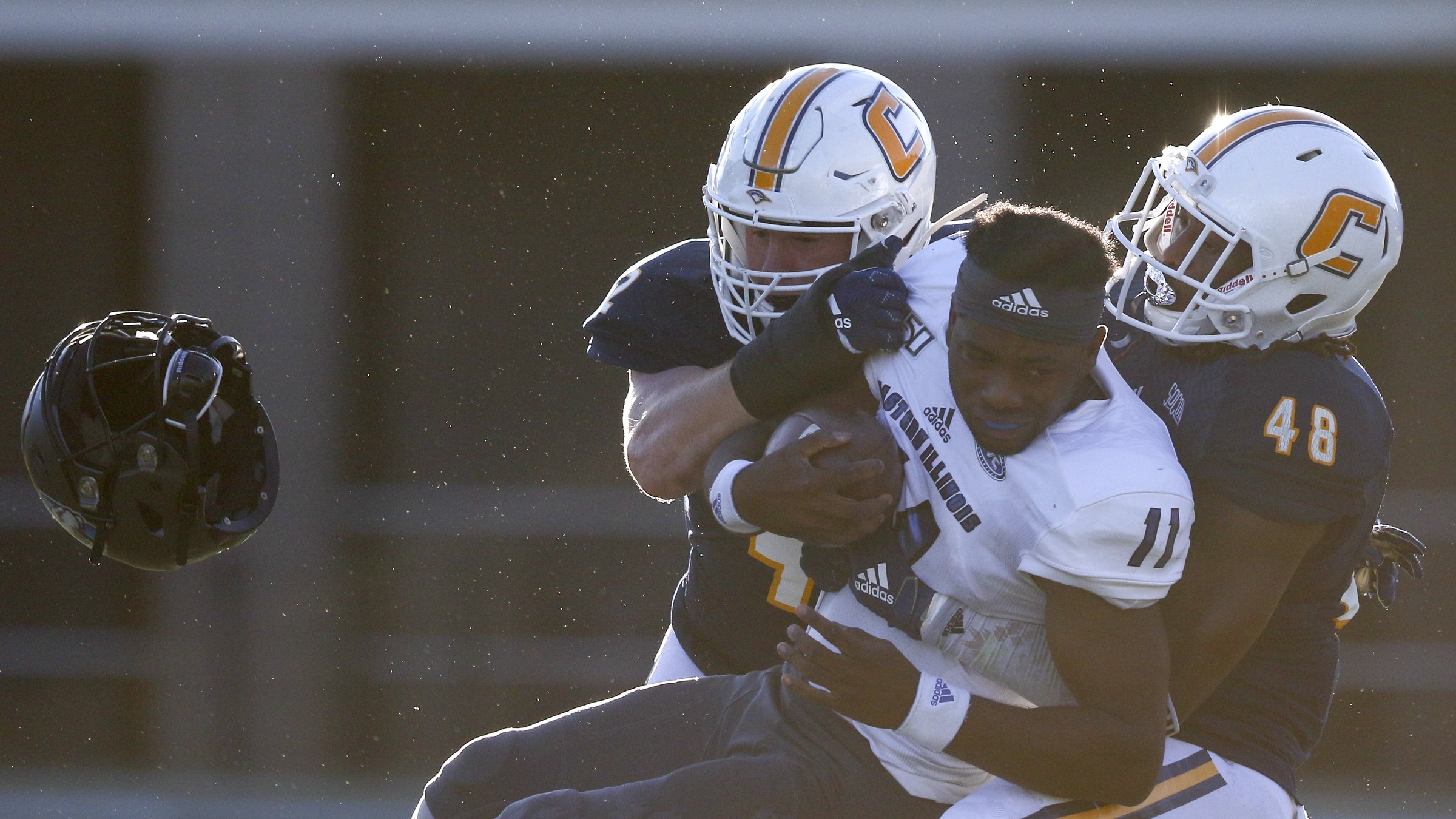 Staff photo by C.B. Schmelter / Eastern Illinois quarterback Johnathan Brantley loses his helmet after being hit by UTC linebackers Marshall Cooper, left, and C.J. Winston on Aug. 29 at Finley Stadium. The Mocs won the season opener 24-10 before losing their next three games, but they have won five of seven since to remain near the top of the SoCon standings during Rusty Wright's first season as head coach at his alma mater.
